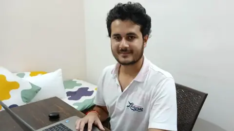 Anurag Garg Anurag Garg sits at his computer wearing a white shirt.